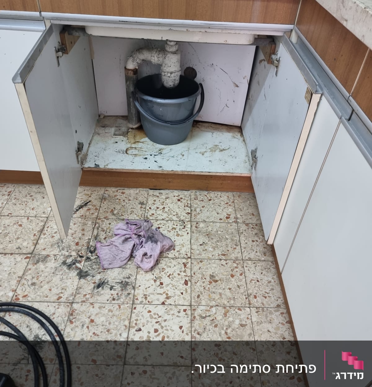 דליפה מתחת לכיור עם דלי ומטלית על הרצפה